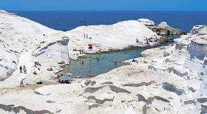1Μήλος: Το Σαρακήνικο Το Σαρακήνικο είναι μια από τις πιο εντυπωσιακότερες παραλίες του Αιγαίου ο ασβεστόλιθος τα λευκά ηφαιστειογενή διαβρωμένα βράχια με το πλήθος των σπηλιών μέχρι το νερό είναι μοναδική εμπειρία που πρέπει να ζήσεις . Παράλληλα το φαλακρό του τοπίου η απουσία οποιασδήποτε βλάστησης και το σεληνιακό τοπίο κάνουν ο τοπίο πραγματικά μοναδικό. 2Πάρος: Κολυμπήθρες Οι Κολυμπήθρες είναι μια από τις πιο διασημότερες παραλίες της χώρας μας και βρίσκετε στον όρμο της Νάουσας. Τα γκριζωπά Βράχια της σε παράξενους σχηματισμούς που φτάνουν ως την ακροθαλασσιά σχηματίζουν μια σειρά από διαδοχικές υπέροχες παραλίες . Τα γαλαζοπράσινα νερά και αμμώδεις ορμίσκοι δημιουργούν ένα μαγικό τοπίο πέρα από κάθε φαντασία . 3Κύθνος: Κολώνα Η παραλία Κολώνα είναι μια πραγματικά ιδιαίτερη και όμορφη παραλία μια στενή αμμουδερή λωρίδα γης που συνδέει την Κύθνο με το νησάκι του Αγίου Λουκά αφήνοντας δυο πανέμορφες αμμουδιές εκατέρωθεν της στεριάς. Η χρυσαφένια άμμος αλλά και τα κρυστάλλινα νερά της σε μαγεύουν τόσο που δεν σε αφήνουν να την χορτάσεις ποτέ . 4Ζάκυνθος: Ναυάγιο Διαχρονικά είναι η εντυπωσιακότερη παραλία της χώρας μας, αλλά και σύμβολο της Ελλάδας στο εξωτερικό. Η απόκρημνοι και επιβλητικοί λευκοί βράχοι και η λευκή άμμος με το σαπισμένο σκαρί δημιουργούν μια από τις ομορφότερες παραλίες του κόσμου σύμφωνα με μεγαλύτερους διεθνείς τουριστικούς οδηγούς. Τόσο τα τουρκουάζ νερά της αλλά και η λευκή της άμμος πλάι από τους επιβλητικούς βράχους δημιουργούν ένα μαγευτικό φυσικό τοπίο. 5Λευκάδα : Πόρτο Κατσίκι στη Ο επιβλητικός βράχος που προστατεύει την παραλία αλλά και το ψιλό λευκό βοτσαλάκι της σε συνδυασμό με το απίθανο χρώμα των νερών δημιουργεί ένα μαγικό τοπίο. Την έχουν κατάταξη όλοι οι ταξιδιωτικοί οδηγοί μονίμως και όχι άδικα στις καλύτερες παραλίες της Ευρώπης.